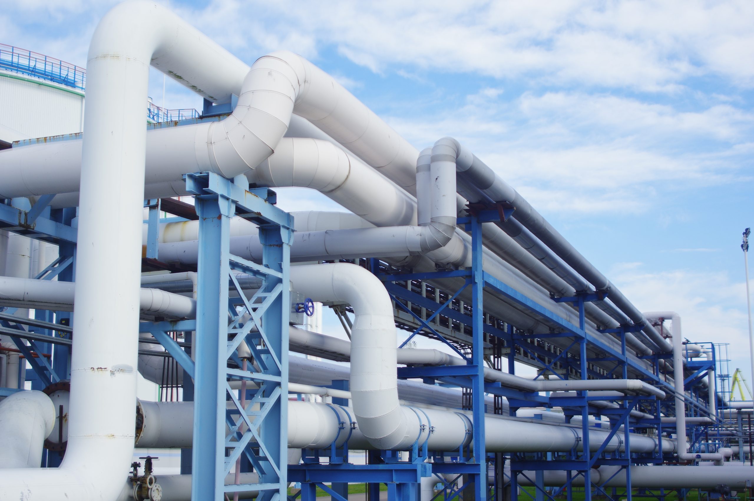 A closeup of industrial pipelines around a factor on a sunny day